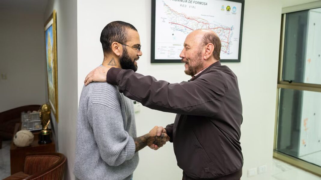 Dani Alves y Gildo Insfrán se dan la mano en un despacho con un mapa de Formosa en la pared