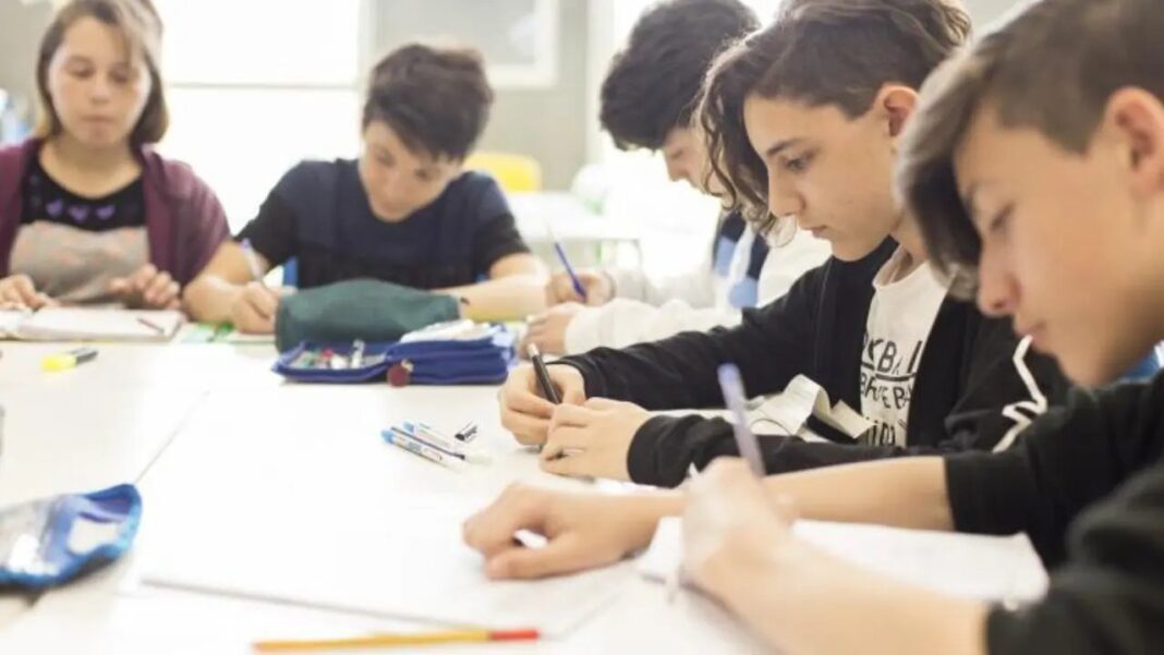 Solo 19 de cada 100 chicos de 15 años llegan a tiempo y con lo básico aprendido Adolescentes de secundaria escriben en sus carpetas alrededor de una mesa en un aula