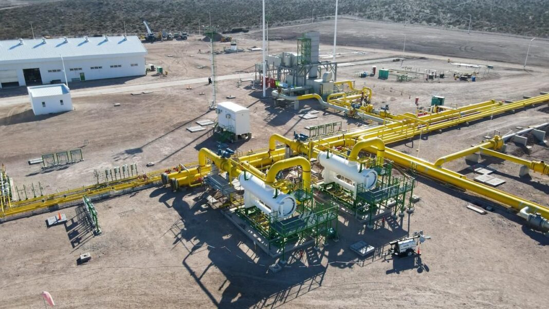 Vista aérea de una planta de tratamiento de gas con cañerías amarillas en un terreno árido