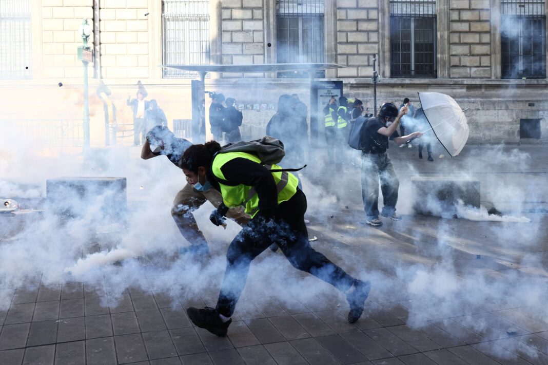 Manifestantes corren entre gases lacrimógenos durante una protesta callejera