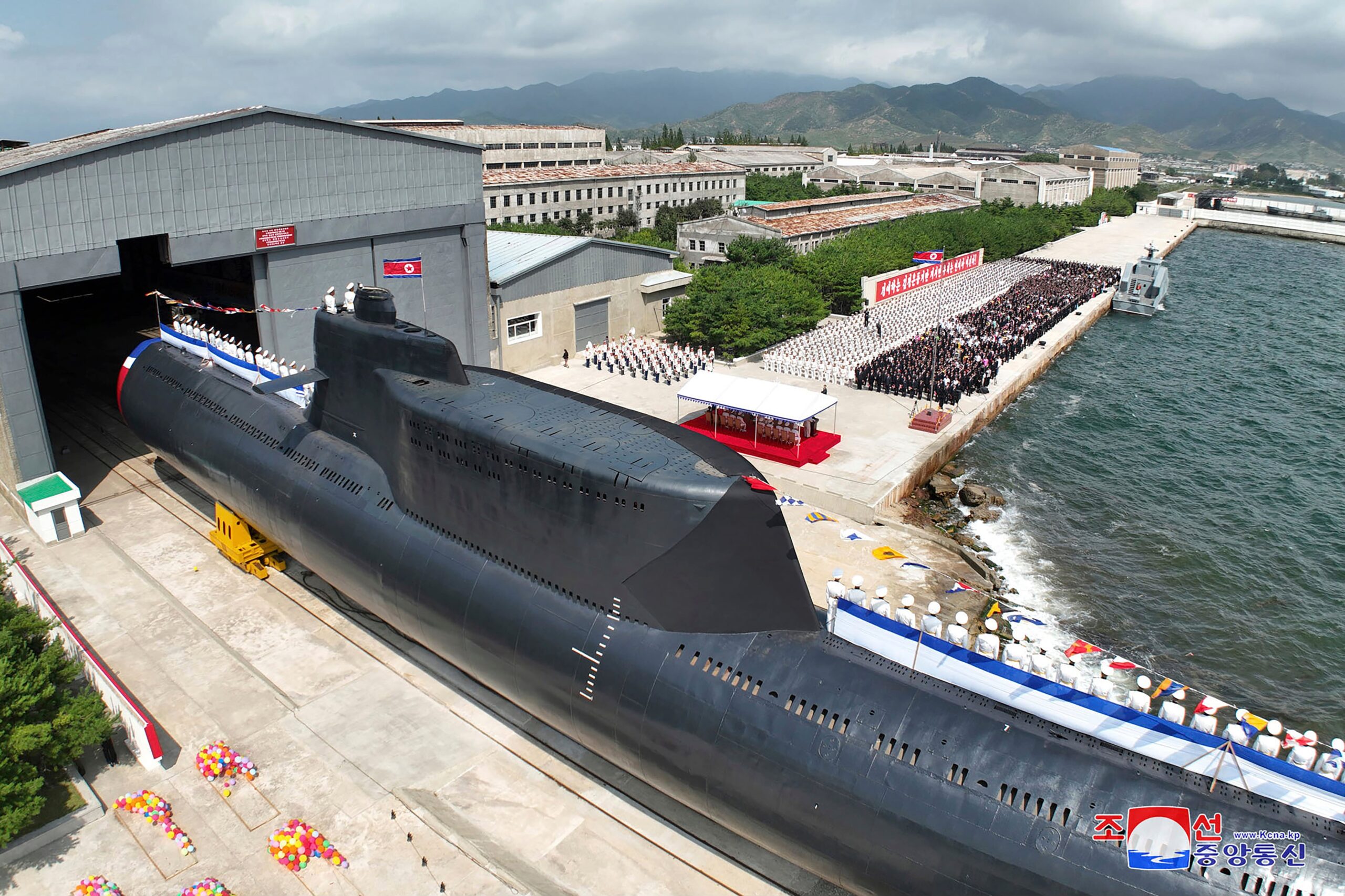 Un submarino de gran porte amarrado en un muelle, con público reunido junto al mar